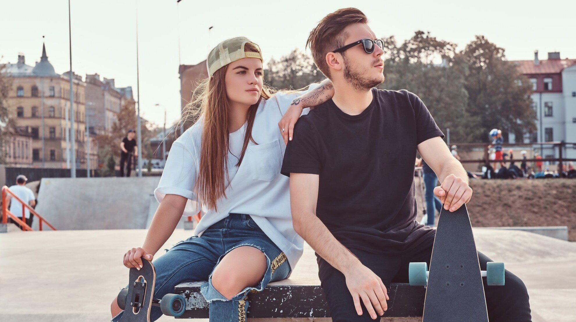 young-stylish-couple-of-a-trendy-dressed-skaters-relaxing-at-skatepark